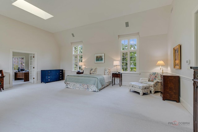 carpeted bedroom featuring high vaulted ceiling, multiple windows, a skylight, and baseboards