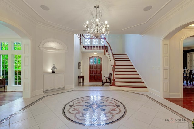 tiled entryway with arched walkways, crown molding, stairway, and baseboards