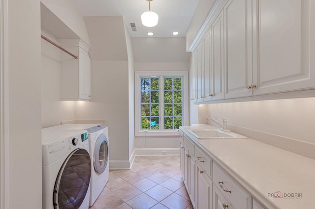 clothes washing area featuring a sink, visible vents, baseboards, cabinet space, and washer and clothes dryer