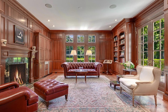 sitting room with wooden walls, ornamental molding, a high end fireplace, and built in features