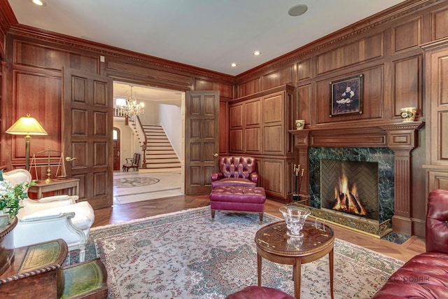 living area featuring a decorative wall, wooden walls, a premium fireplace, stairway, and crown molding