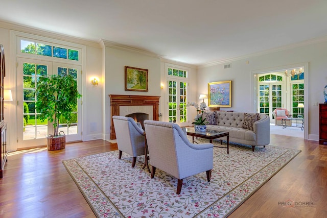 living room featuring crown molding, a fireplace, visible vents, wood finished floors, and plenty of natural light