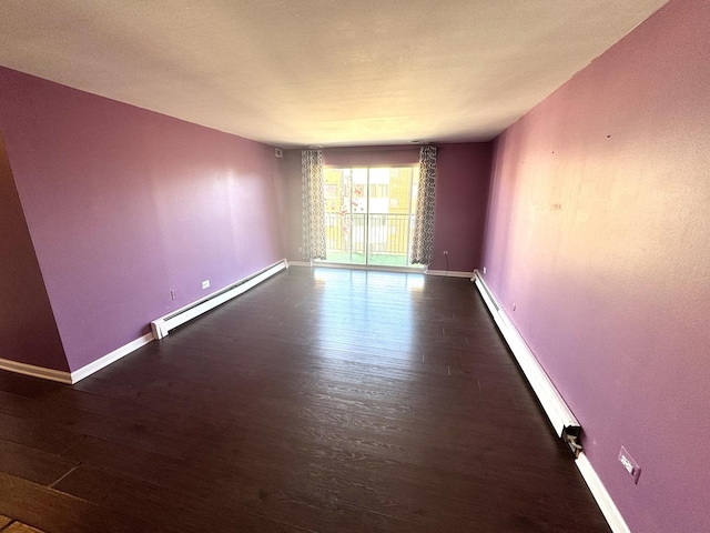 empty room featuring a baseboard radiator, baseboards, and wood finished floors