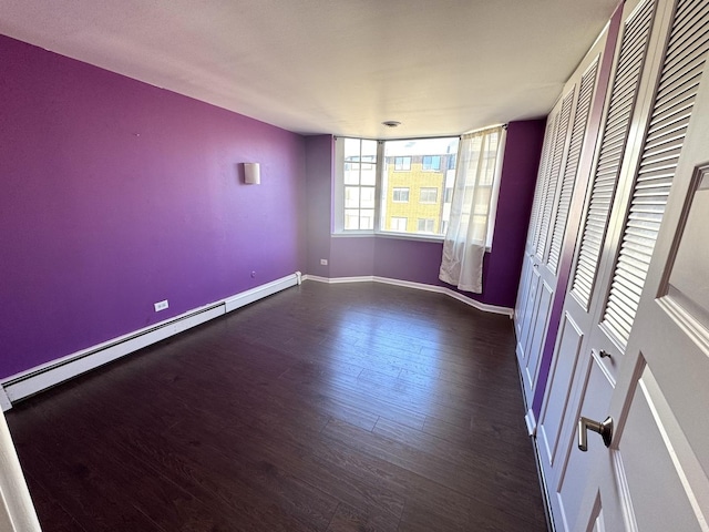 spare room with baseboards, baseboard heating, and wood finished floors