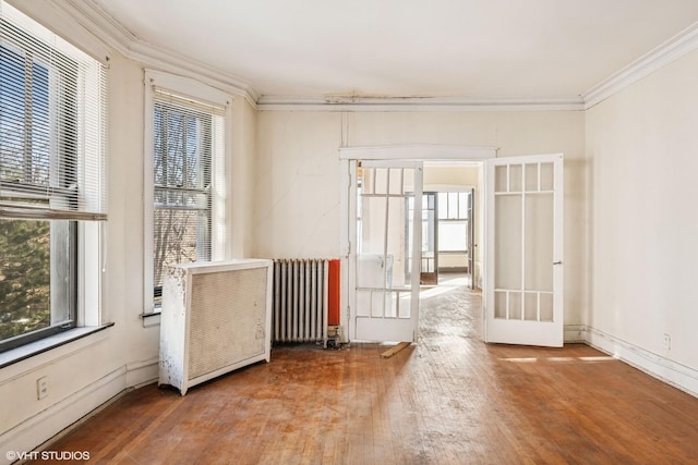 spare room with radiator heating unit, wood finished floors, french doors, and ornamental molding