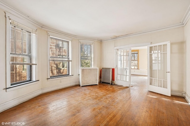 unfurnished room featuring hardwood / wood-style flooring, french doors, radiator, crown molding, and baseboards