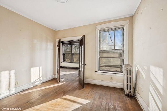 unfurnished room featuring crown molding, radiator heating unit, baseboards, and wood-type flooring