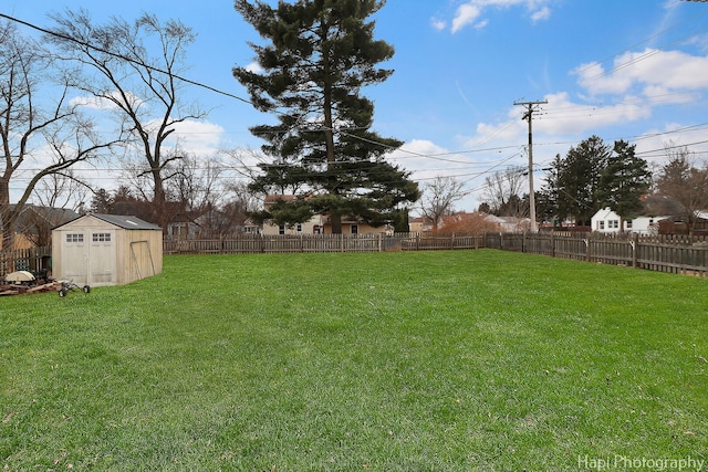 view of yard with a shed, a fenced backyard, and an outdoor structure