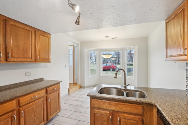 kitchen with dark stone countertops, visible vents, a sink, pendant lighting, and brown cabinets