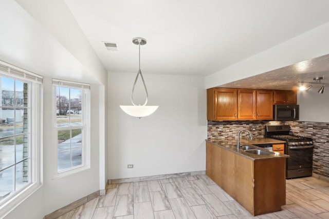 kitchen with brown cabinets, a sink, backsplash, a peninsula, and stainless steel gas range