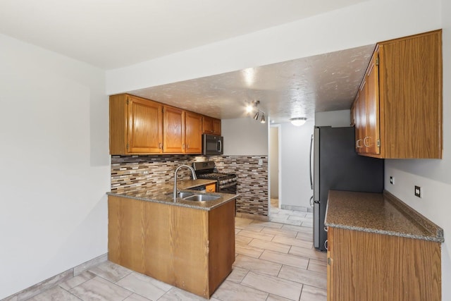 kitchen with backsplash, brown cabinets, stainless steel appliances, a textured ceiling, and a sink