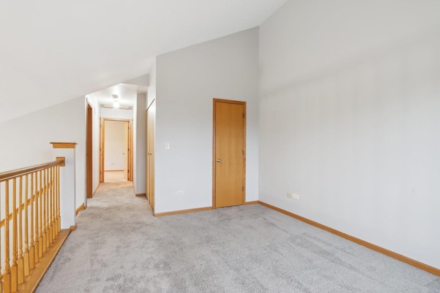 interior space with light colored carpet, lofted ceiling, and baseboards