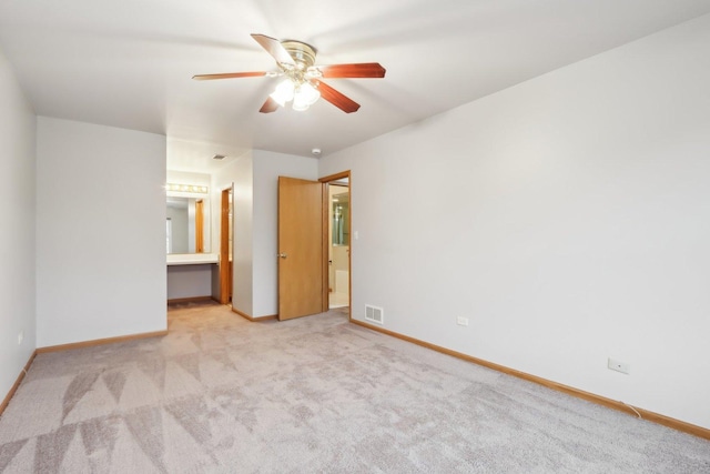 unfurnished bedroom featuring visible vents, baseboards, carpet floors, ensuite bath, and a ceiling fan