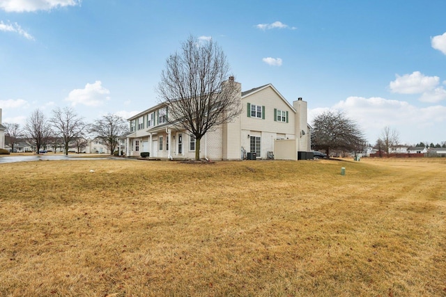 view of front of house featuring central AC unit, a chimney, and a front lawn