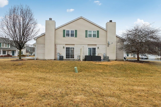 rear view of house with central air condition unit, a lawn, and a chimney