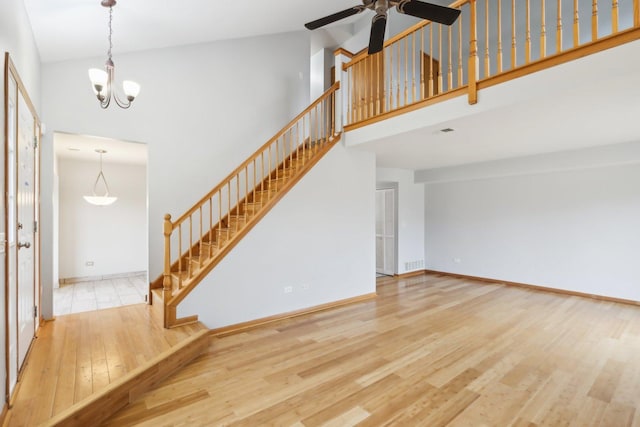 unfurnished living room featuring visible vents, stairs, a high ceiling, and wood finished floors