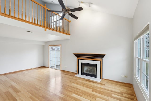 unfurnished living room with visible vents, a tile fireplace, baseboards, and wood finished floors