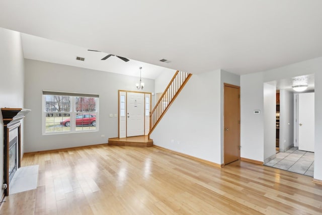 unfurnished living room featuring light wood-type flooring, visible vents, a fireplace, and stairway