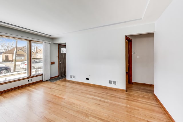 unfurnished room with light wood-style floors, visible vents, and baseboards