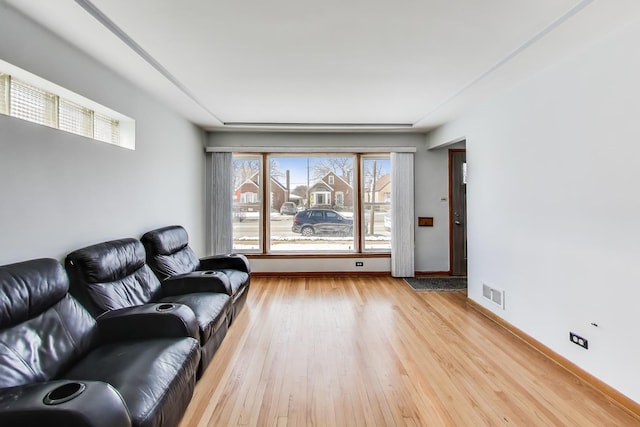 living room with light wood finished floors, baseboards, and visible vents