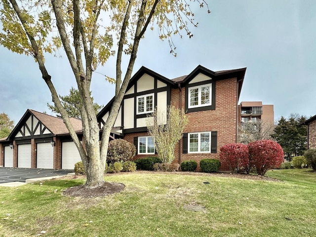 tudor house with an attached garage, brick siding, a front yard, and stucco siding