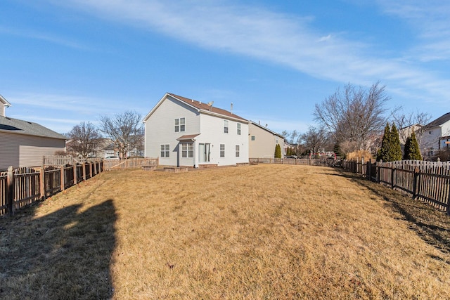 back of house featuring a fenced backyard and a lawn