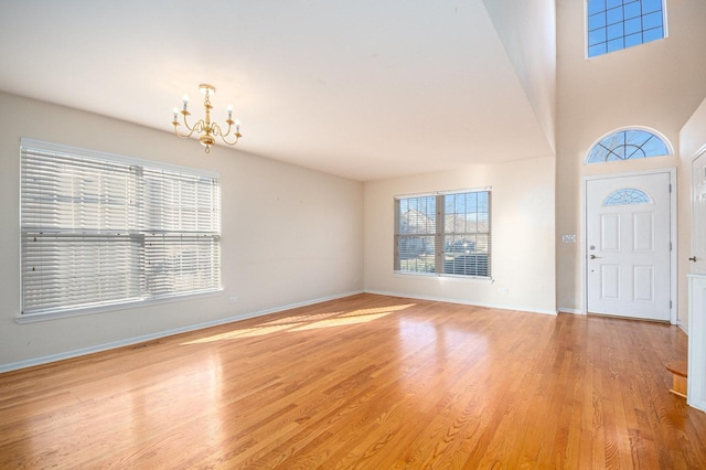 entryway featuring light wood-type flooring, a notable chandelier, and baseboards