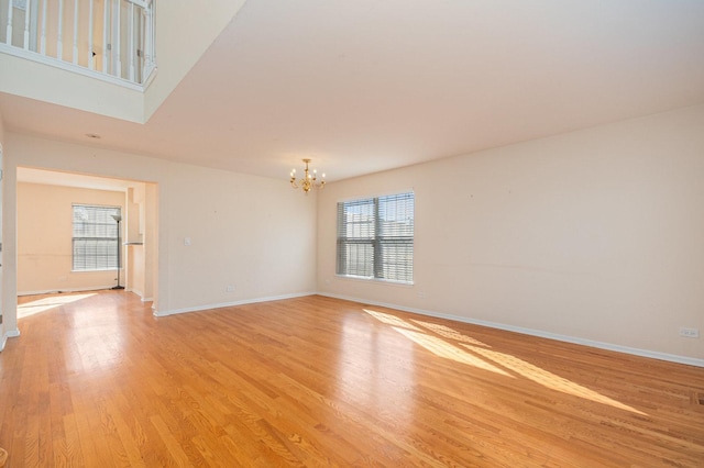 empty room with baseboards, light wood finished floors, and a notable chandelier