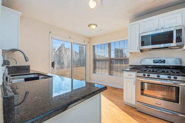 kitchen featuring stainless steel appliances, light wood-style floors, white cabinetry, and a sink