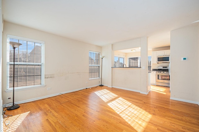 unfurnished room with light wood finished floors, a wealth of natural light, and baseboards