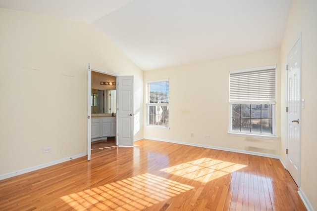 empty room with lofted ceiling, plenty of natural light, wood-type flooring, and baseboards