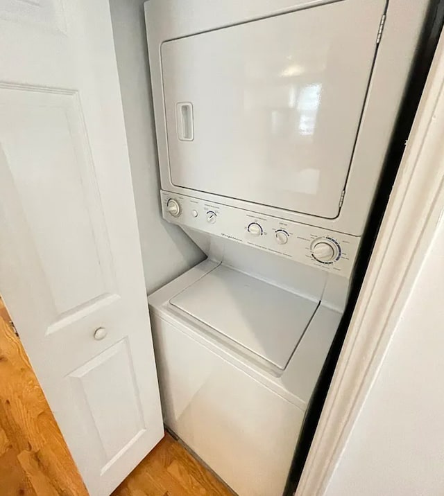 laundry area with laundry area, light wood finished floors, and stacked washer / drying machine