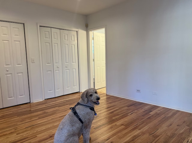 unfurnished bedroom with multiple closets and wood finished floors