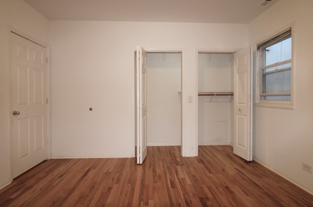 unfurnished bedroom featuring multiple closets and wood finished floors