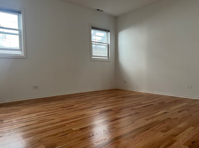 spare room featuring plenty of natural light, visible vents, and wood finished floors