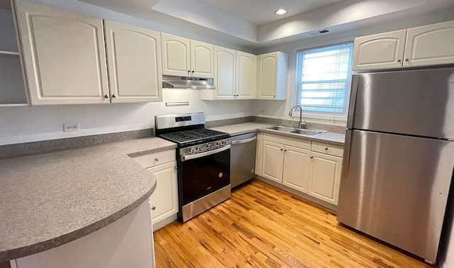 kitchen featuring stainless steel appliances, visible vents, light wood-style flooring, a sink, and under cabinet range hood