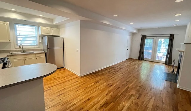 kitchen featuring freestanding refrigerator, a healthy amount of sunlight, a sink, and light wood finished floors