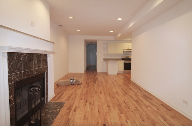 unfurnished living room with recessed lighting, a tiled fireplace, and light wood-style floors