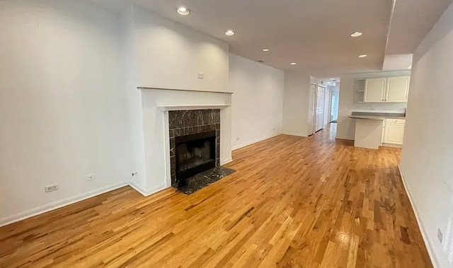 unfurnished living room with light wood finished floors, a fireplace, baseboards, and recessed lighting