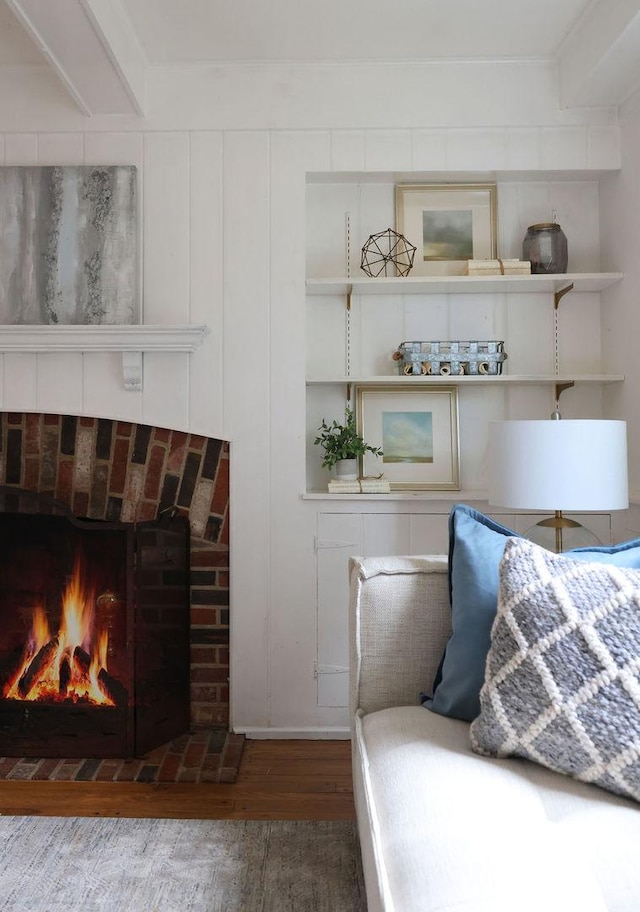 bedroom with a fireplace, a decorative wall, and wood finished floors