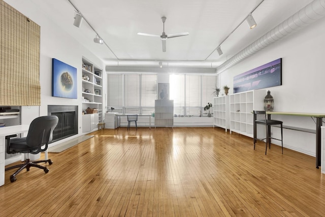 home office with built in features, track lighting, and hardwood / wood-style flooring