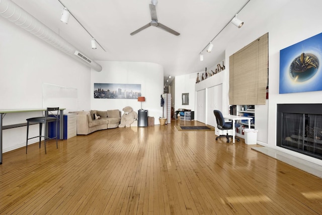 interior space featuring a fireplace with raised hearth, ceiling fan, wood-type flooring, and track lighting