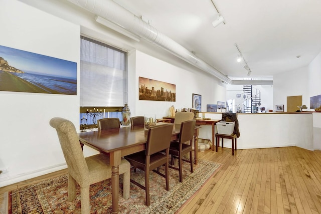 dining room with light wood-type flooring, rail lighting, and stairway