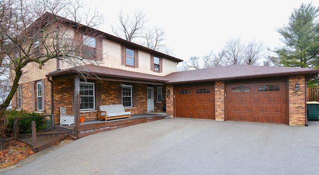 view of front of house featuring a porch, brick siding, an attached garage, and aphalt driveway