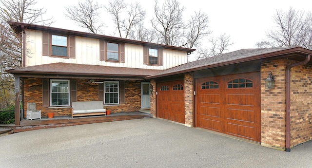 view of front of house with aphalt driveway, brick siding, covered porch, an attached garage, and board and batten siding