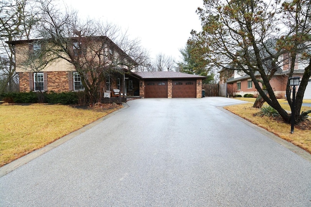 view of front of house featuring an attached garage, brick siding, fence, driveway, and a front lawn