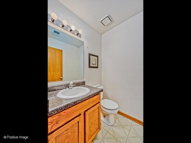 half bath with vanity, baseboards, visible vents, tile patterned floors, and toilet