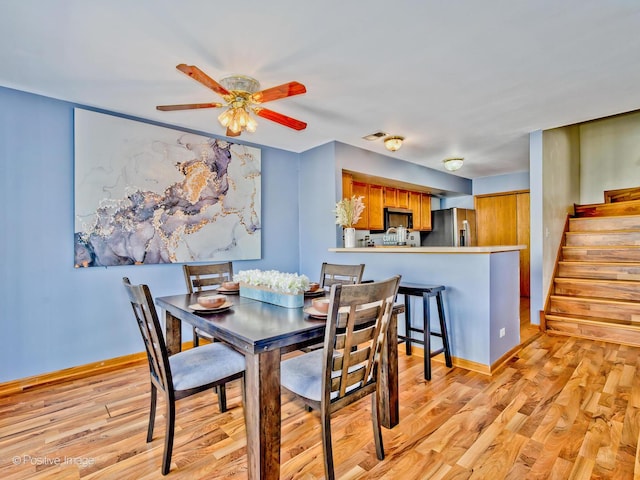 dining space with stairway, baseboards, light wood finished floors, and ceiling fan