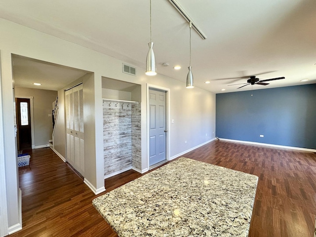 empty room with dark wood-style floors, visible vents, and baseboards