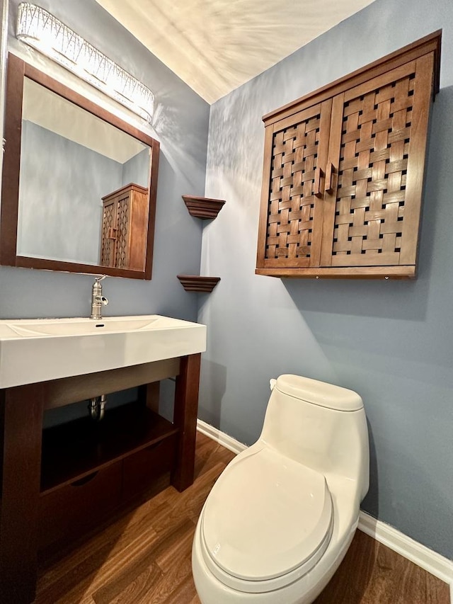 bathroom with wood finished floors, toilet, and baseboards